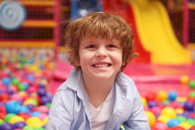 Photo of Happy little boy in ball pit. Kid's play room