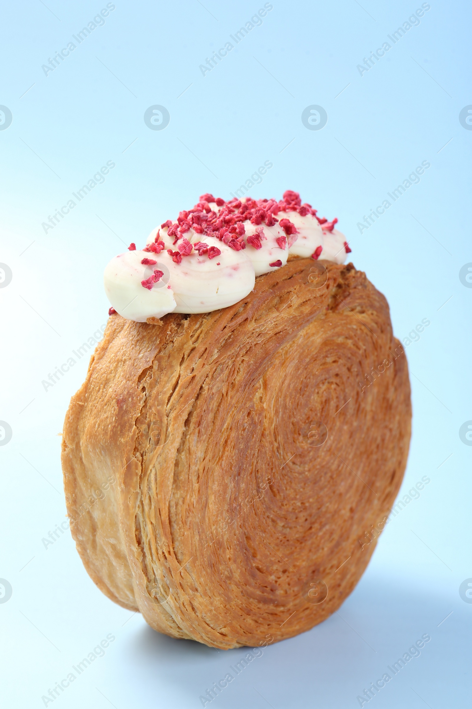 Photo of One supreme croissant with cream on light blue background, closeup. Tasty puff pastry