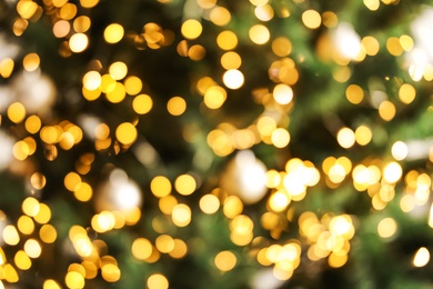 Photo of Blurred view of Christmas tree with bright fairy lights, closeup. Bokeh effect