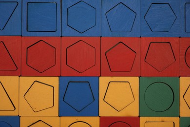 Photo of Wooden puzzle with different geometric shapes and colors as background, top view. Montessori toy