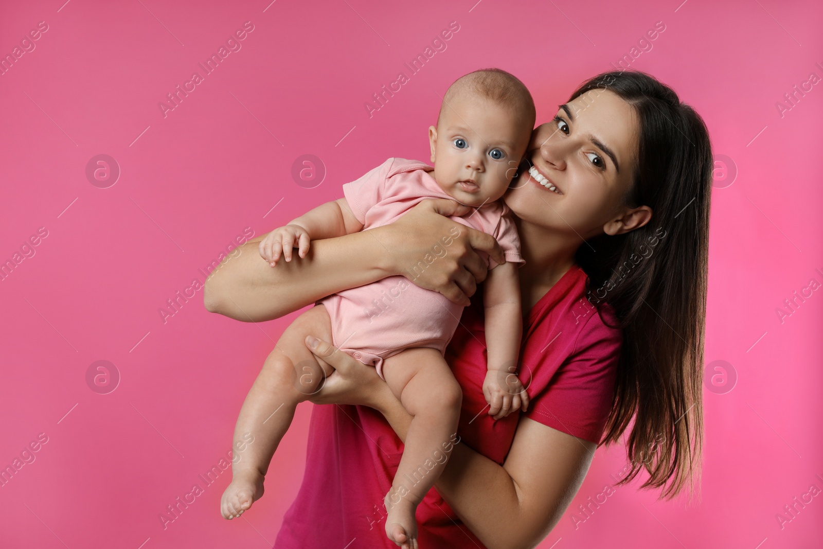 Photo of Beautiful mother with her cute baby on pink background