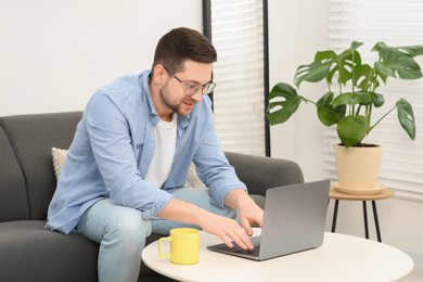 Man working with laptop at table in living room