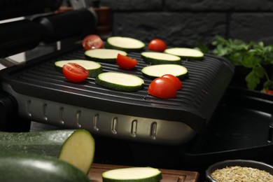 Photo of Electric grill with vegetables on table, closeup