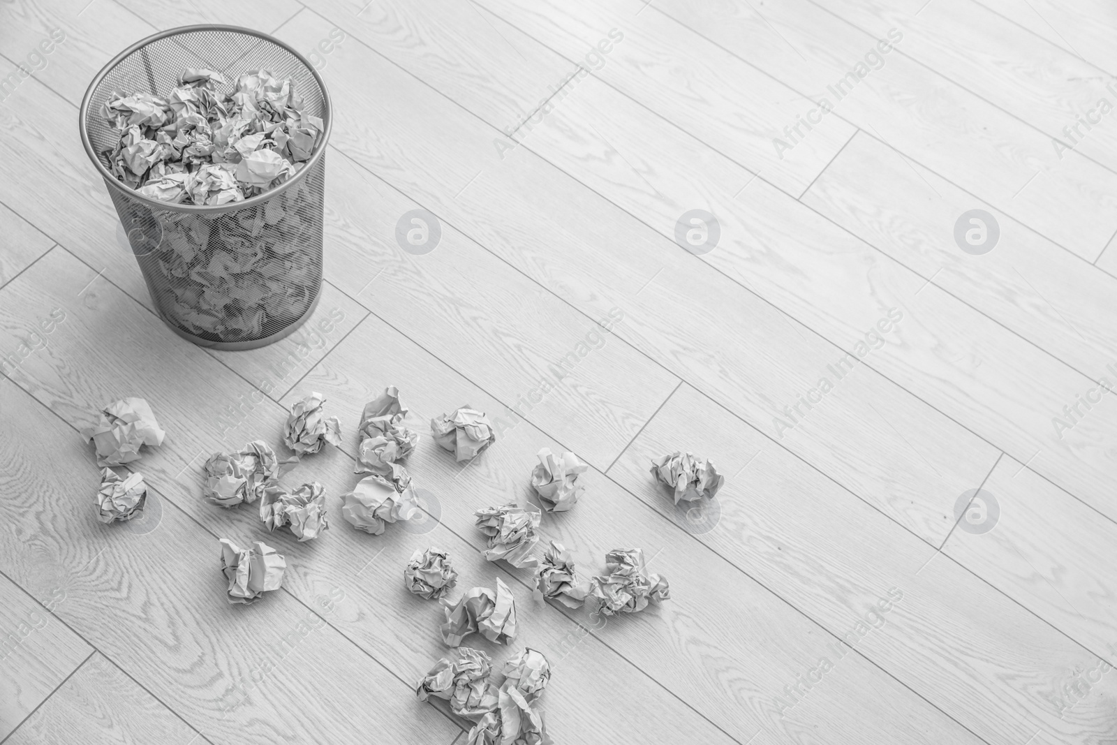 Photo of Metal bin and crumpled paper on floor, above view. Space for text