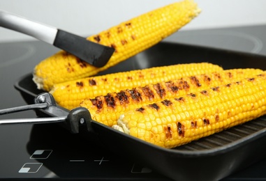 Photo of Cooking fresh corn cobs on grill pan, closeup