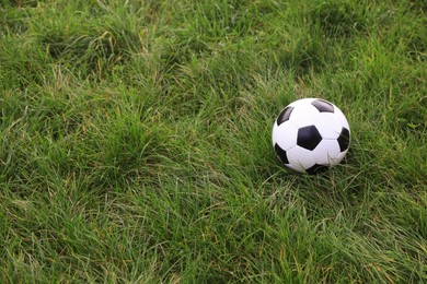 Dirty soccer ball on green grass outdoors, space for text