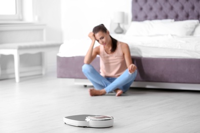 Photo of Scales on floor and sad young woman at home. Weight loss motivation