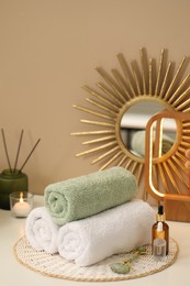 Photo of Spa composition. Rolled towels, cosmetic products and face roller on table