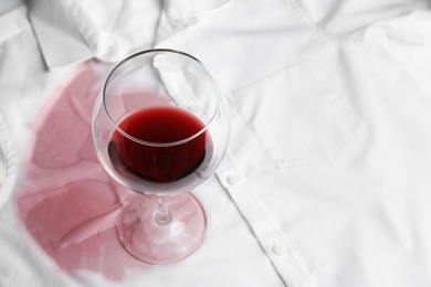 Photo of Transparent glass and spilled exquisite red wine on white shirt. Space for text