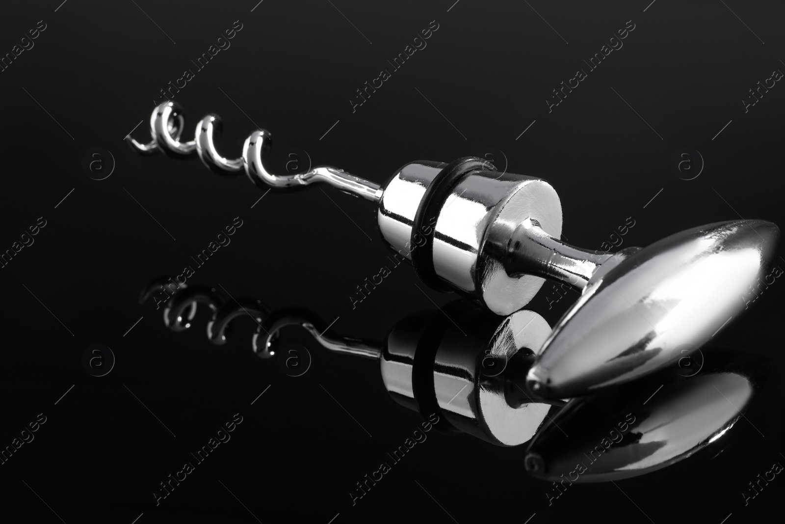 Photo of One metal corkscrew on dark mirror surface, closeup