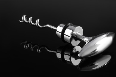 Photo of One metal corkscrew on dark mirror surface, closeup