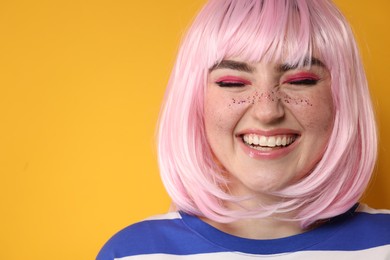 Photo of Smiling woman with bright makeup and glitter freckles on yellow background, closeup. Space for text