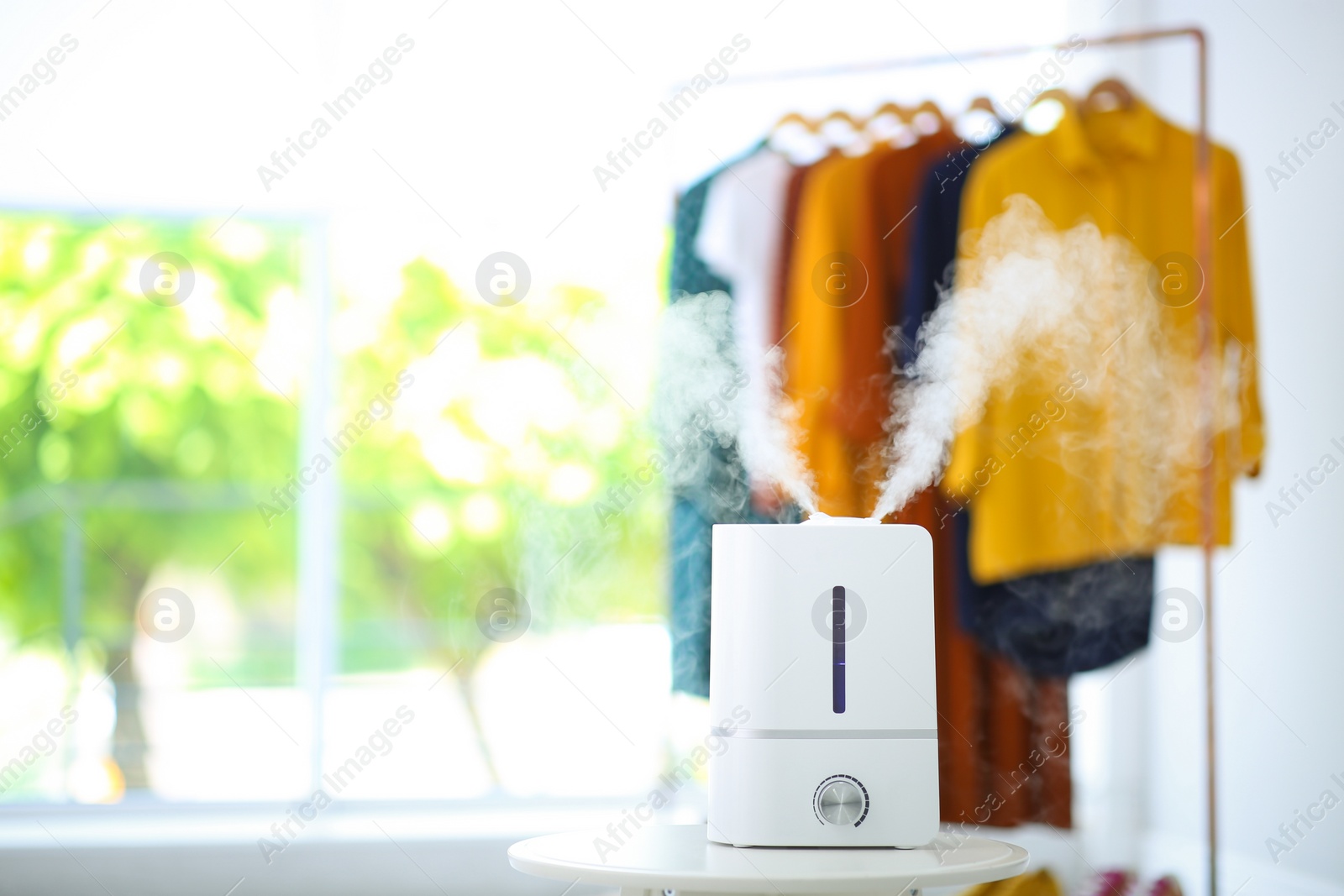 Photo of Modern air humidifier on table indoors. Space for text