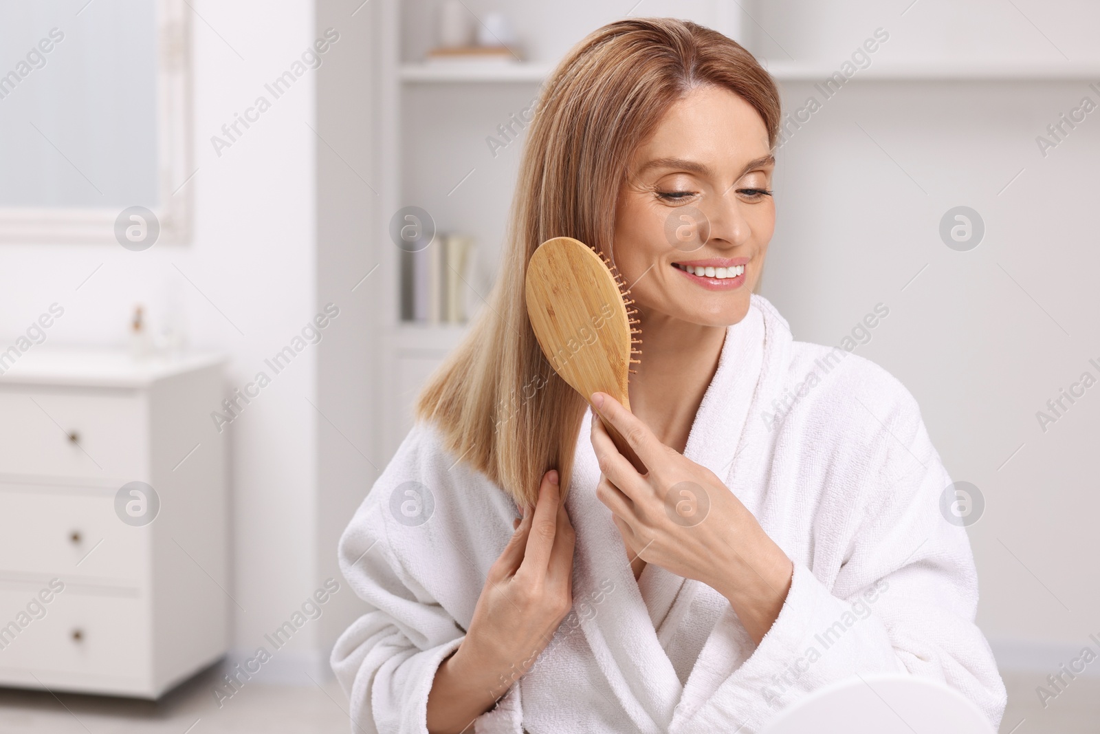 Photo of Beautiful woman brushing her hair in room