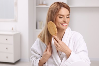 Beautiful woman brushing her hair in room