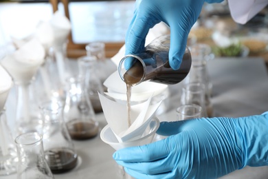 Scientist filtering soil samples at table, closeup. Laboratory analysis