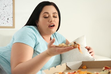 Lazy overweight woman eating pizza at home