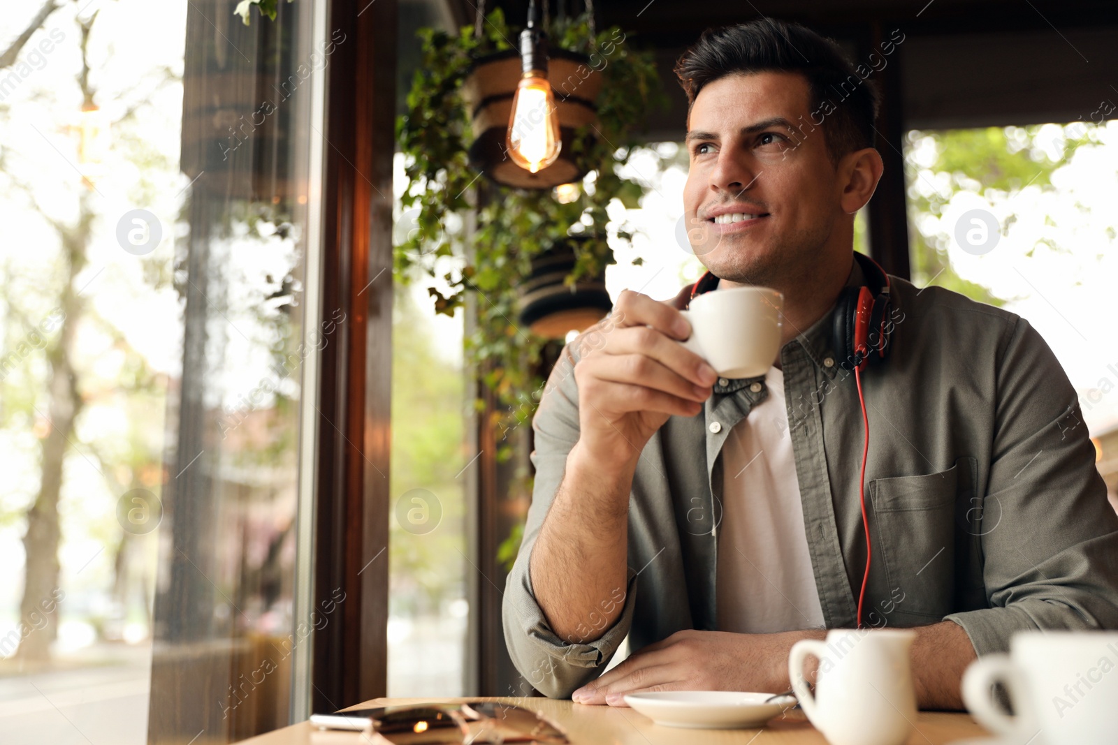 Photo of Handsome man with cup of coffee at cafe in morning