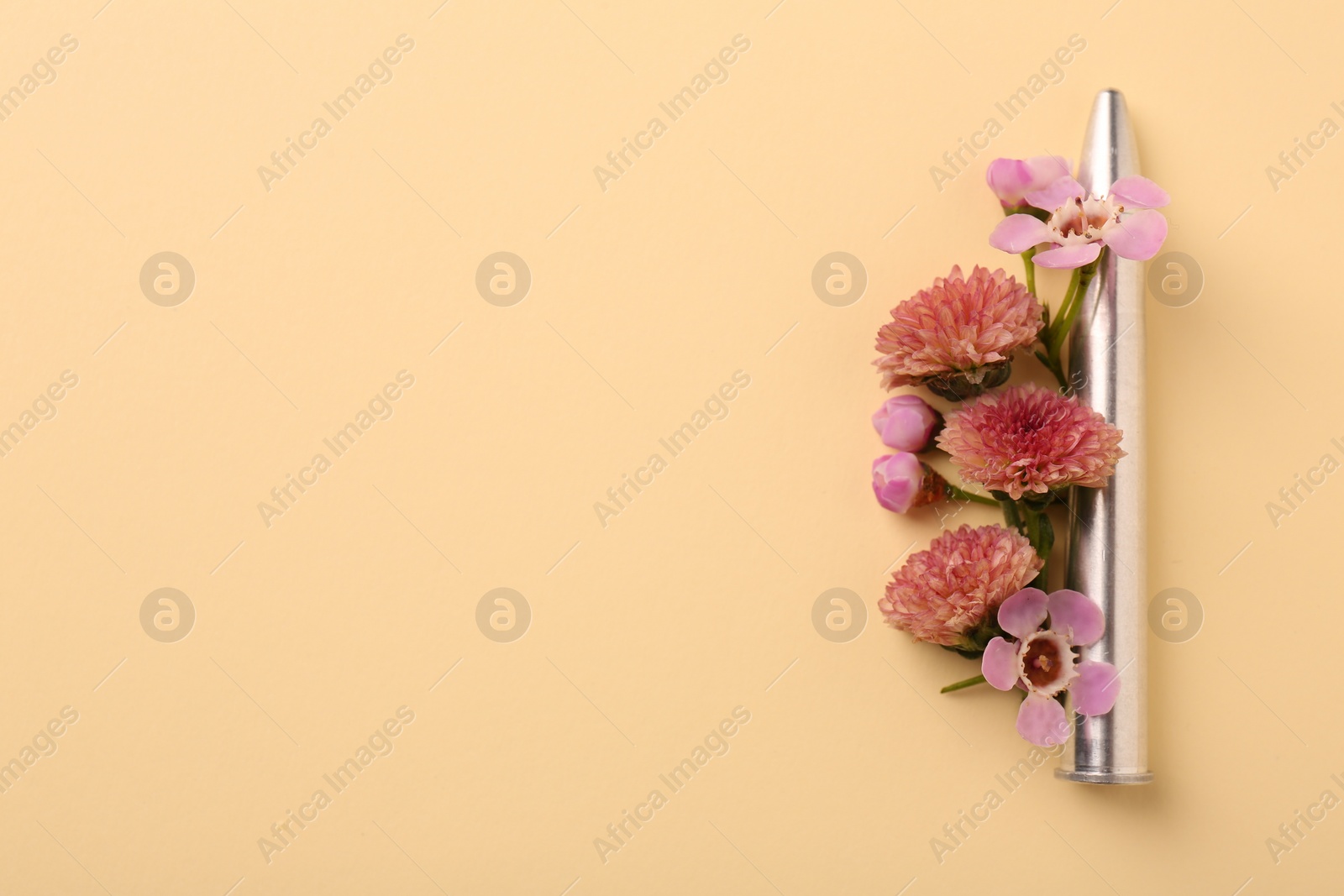 Photo of One bullet and beautiful flowers on yellow background, flat lay. Space for text