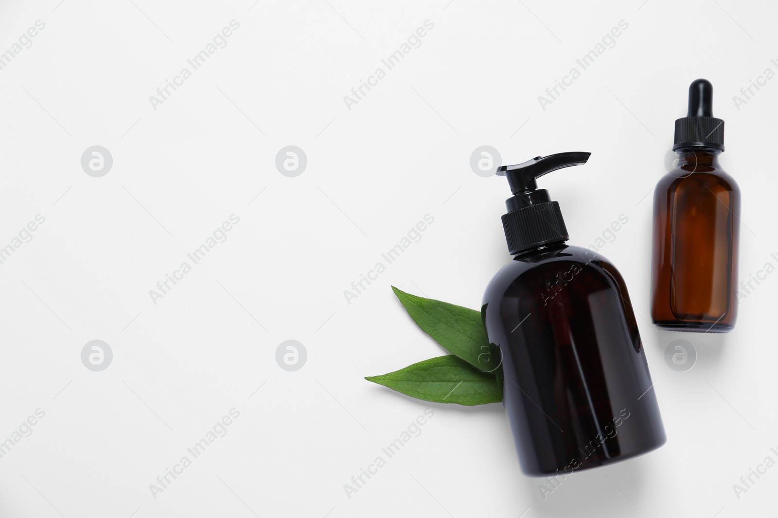 Photo of Bottles with different cosmetic products and green leaves on white background, flat lay. Space for text