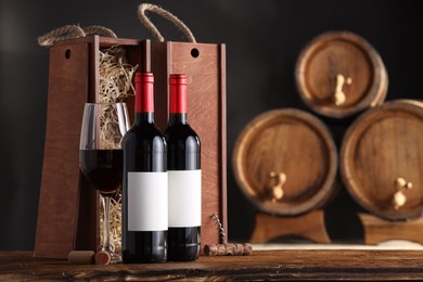 Photo of Wooden boxes, corkscrew and wine bottles on table against dark background. Space for text