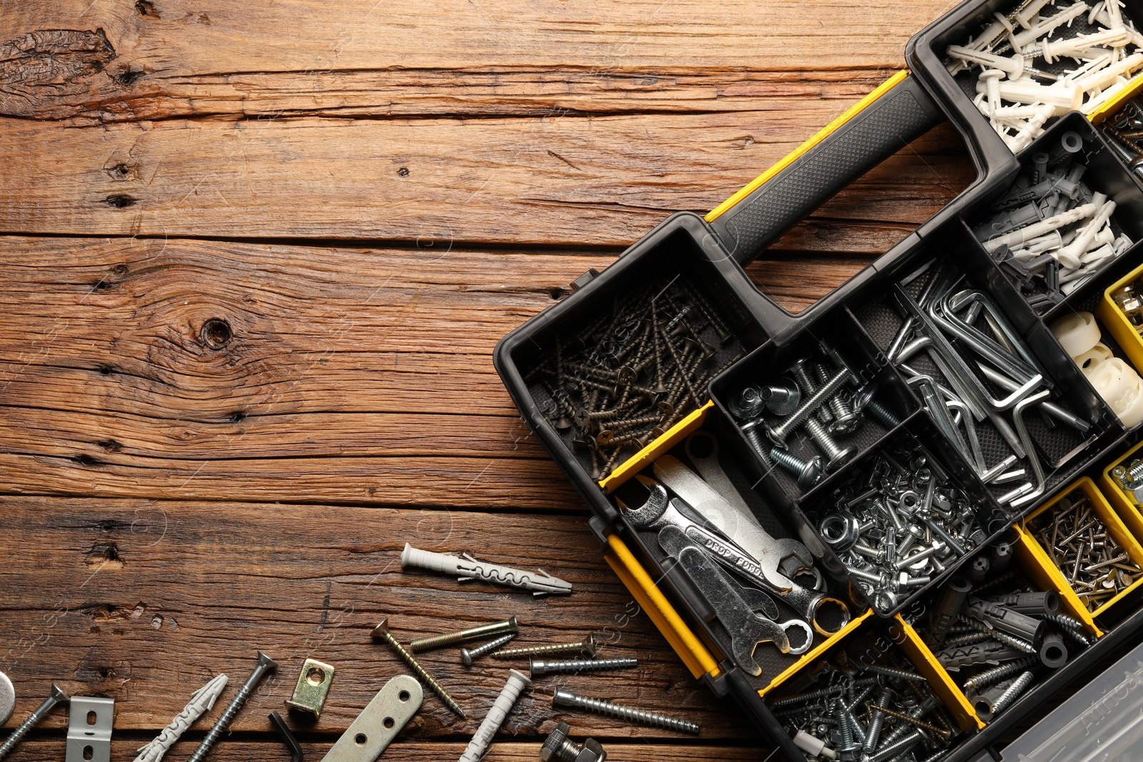 Photo of Organizer with many different fasteners and wrenches on wooden table, flat lay. Space for text