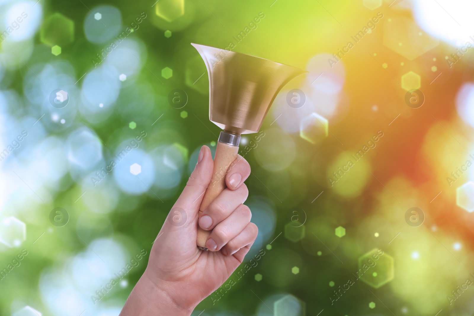 Image of Woman with school bell outdoors, closeup. Bokeh effect