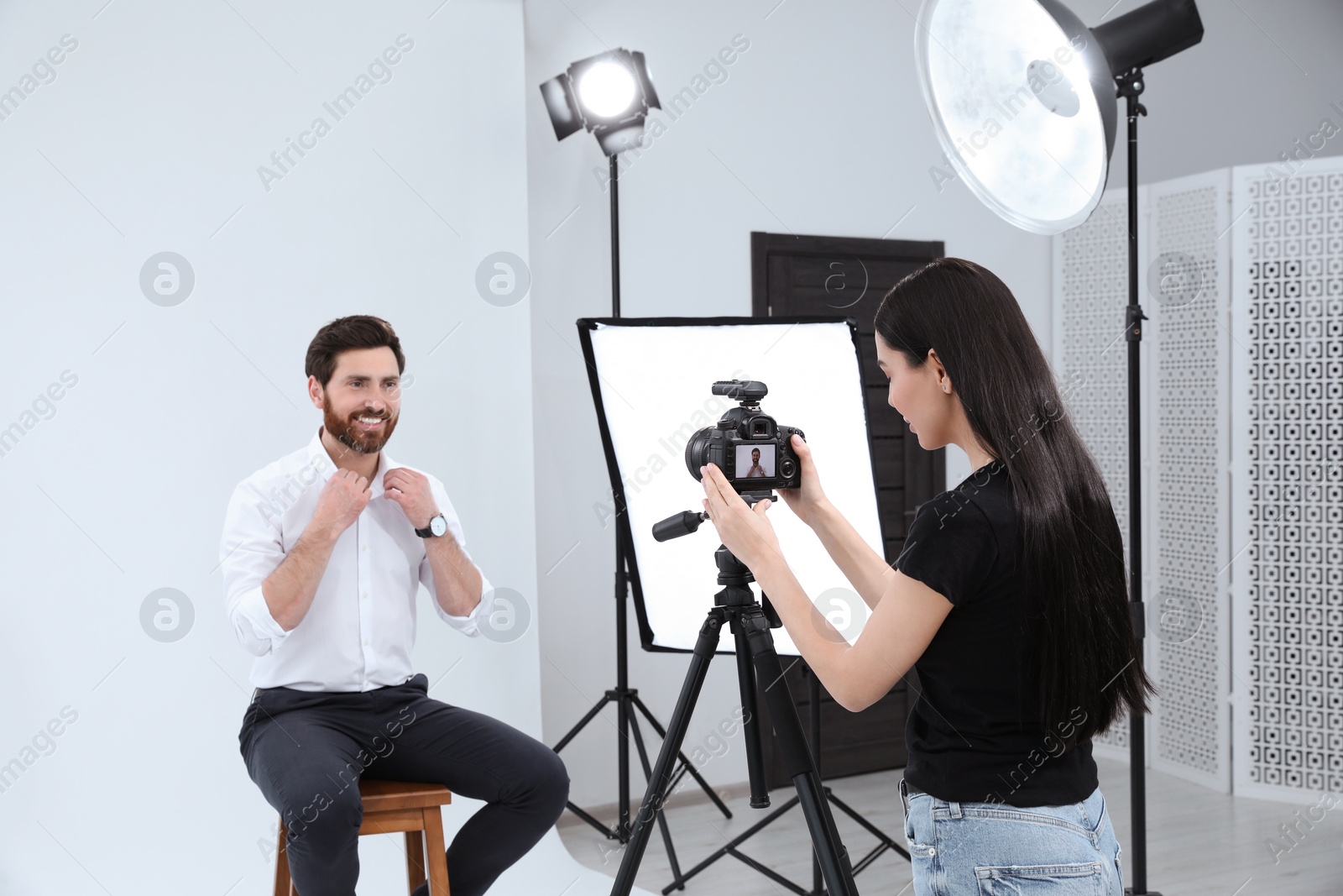 Photo of Professional photographer working with handsome model in modern photo studio