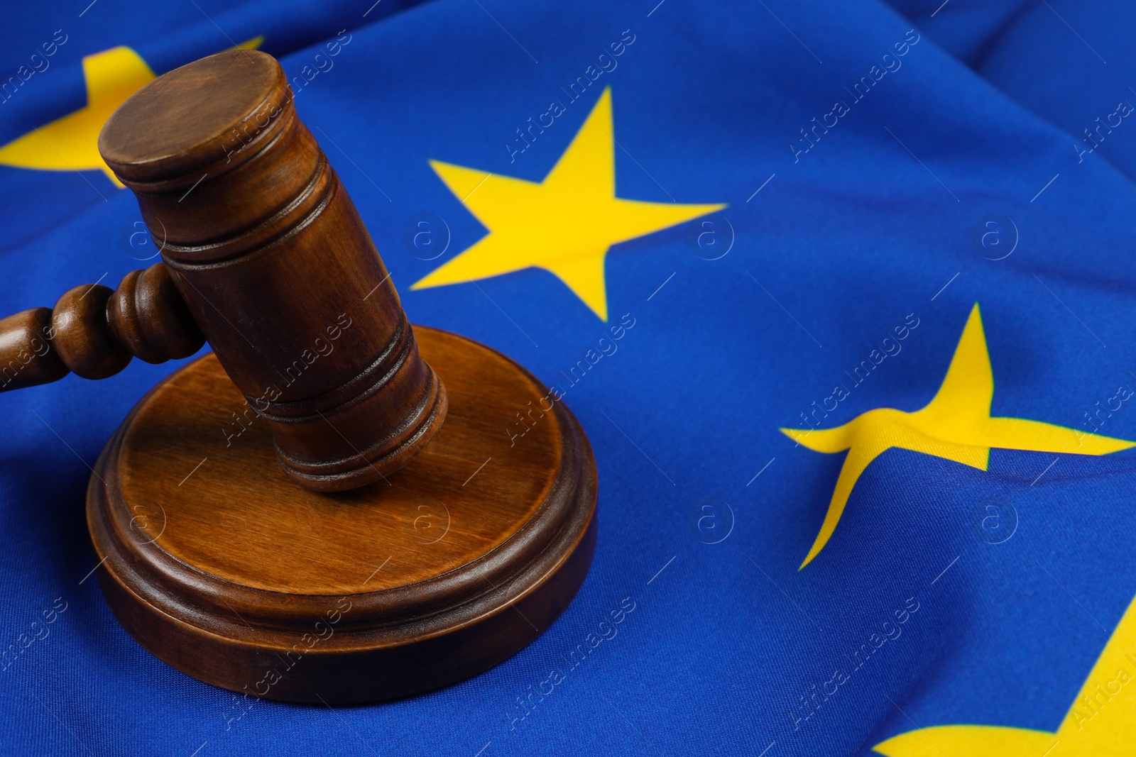 Photo of Wooden judge's gavel on flag of European Union, closeup. Space for text