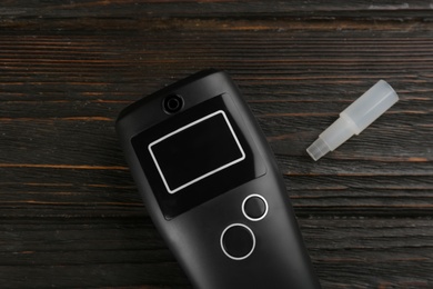 Photo of Modern breathalyzer and mouthpiece on dark wooden background, flat lay
