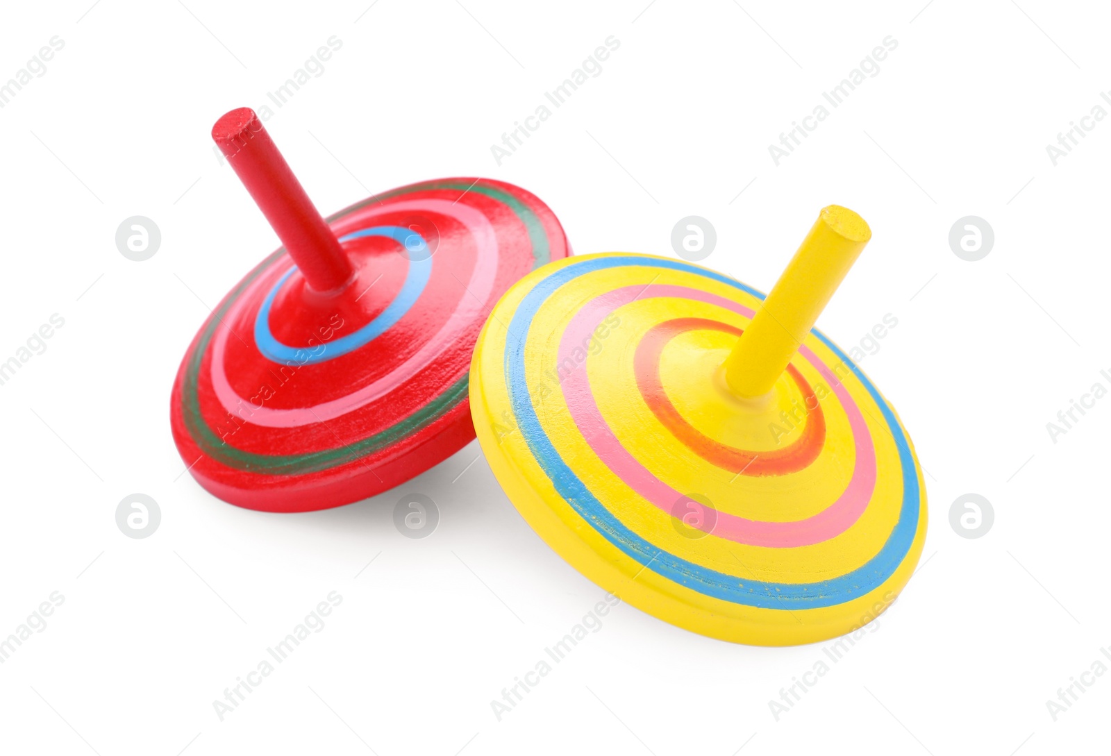 Photo of Two bright spinning tops isolated on white. Toy whirligig