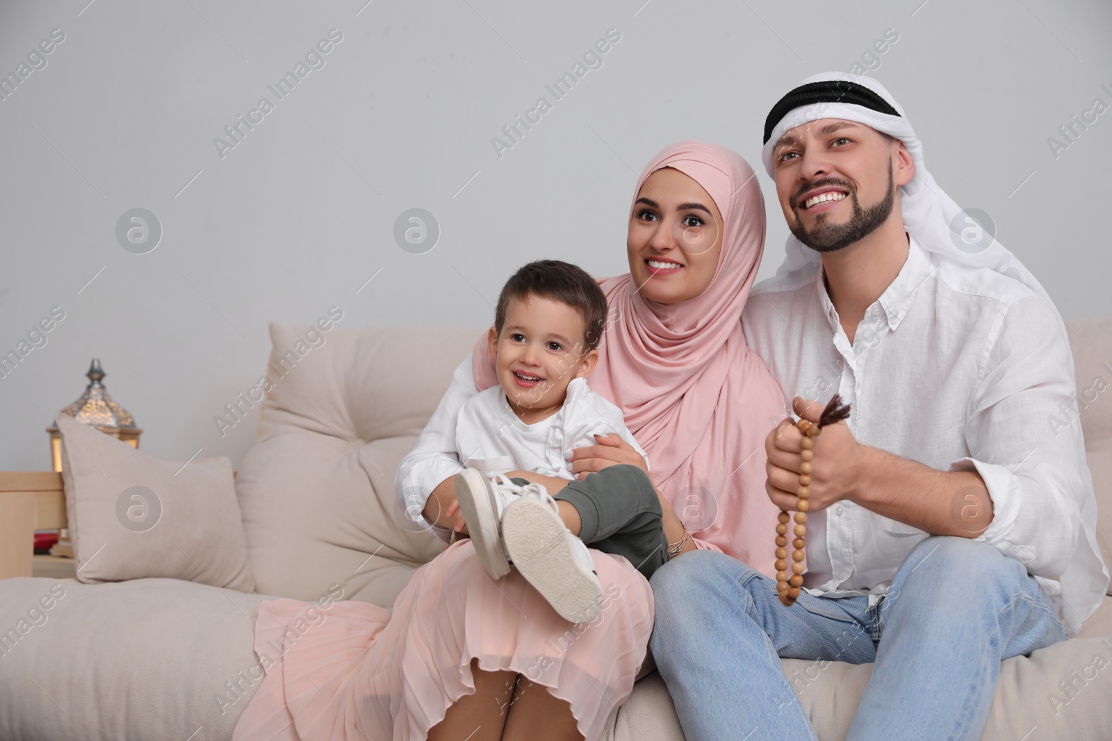 Photo of Happy Muslim family spending time together on sofa at home, space for text