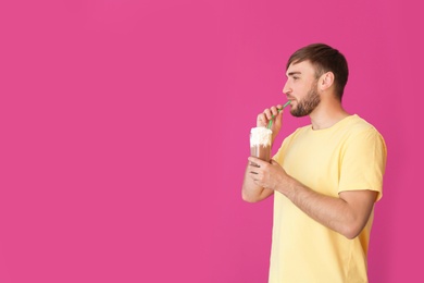 Young man with glass of delicious milk shake on color background