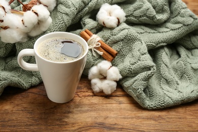 Photo of Composition with hot drink and warm plaid on wooden table