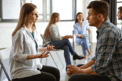 Photo of Psychotherapist working with patient in group therapy session indoors