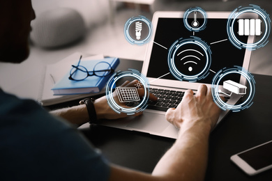 Man using laptop to control smart home, closeup. Automatic systems