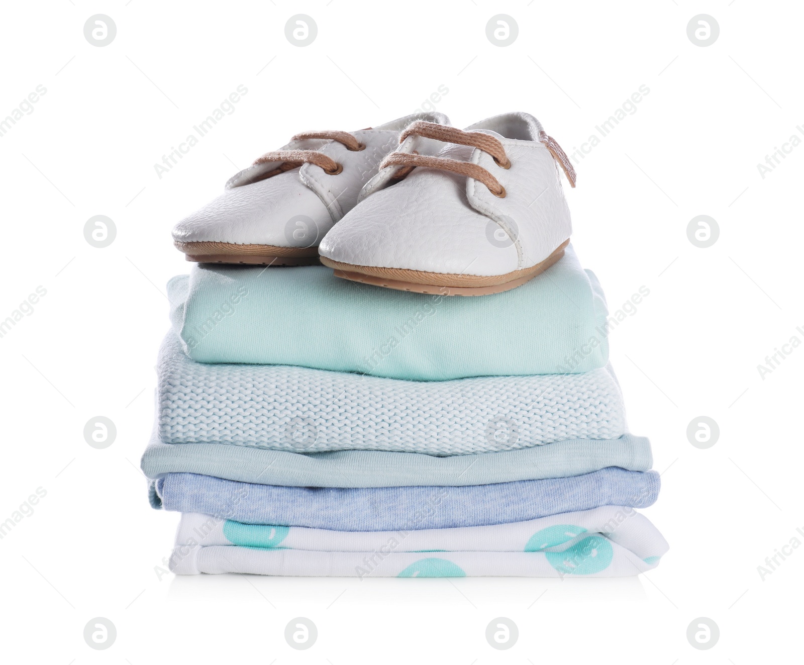 Photo of Stack of clean baby's clothes and small shoes on white background