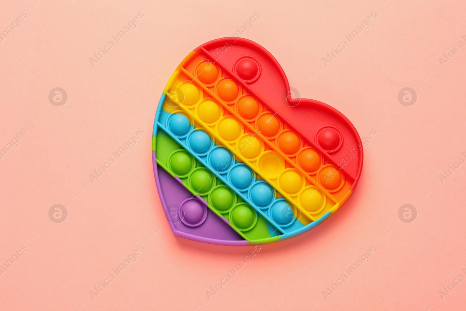Photo of Heart shaped rainbow pop it fidget toy on pink background, top view