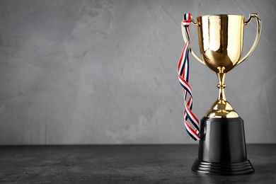 Photo of Golden trophy cup on table grey background. Space for text