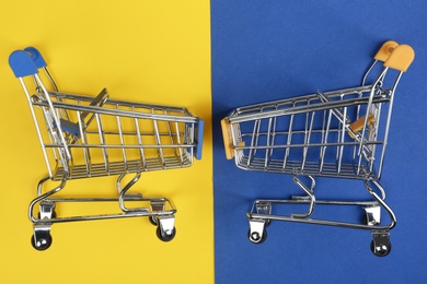 Flat lay composition with empty shopping trolleys on color background