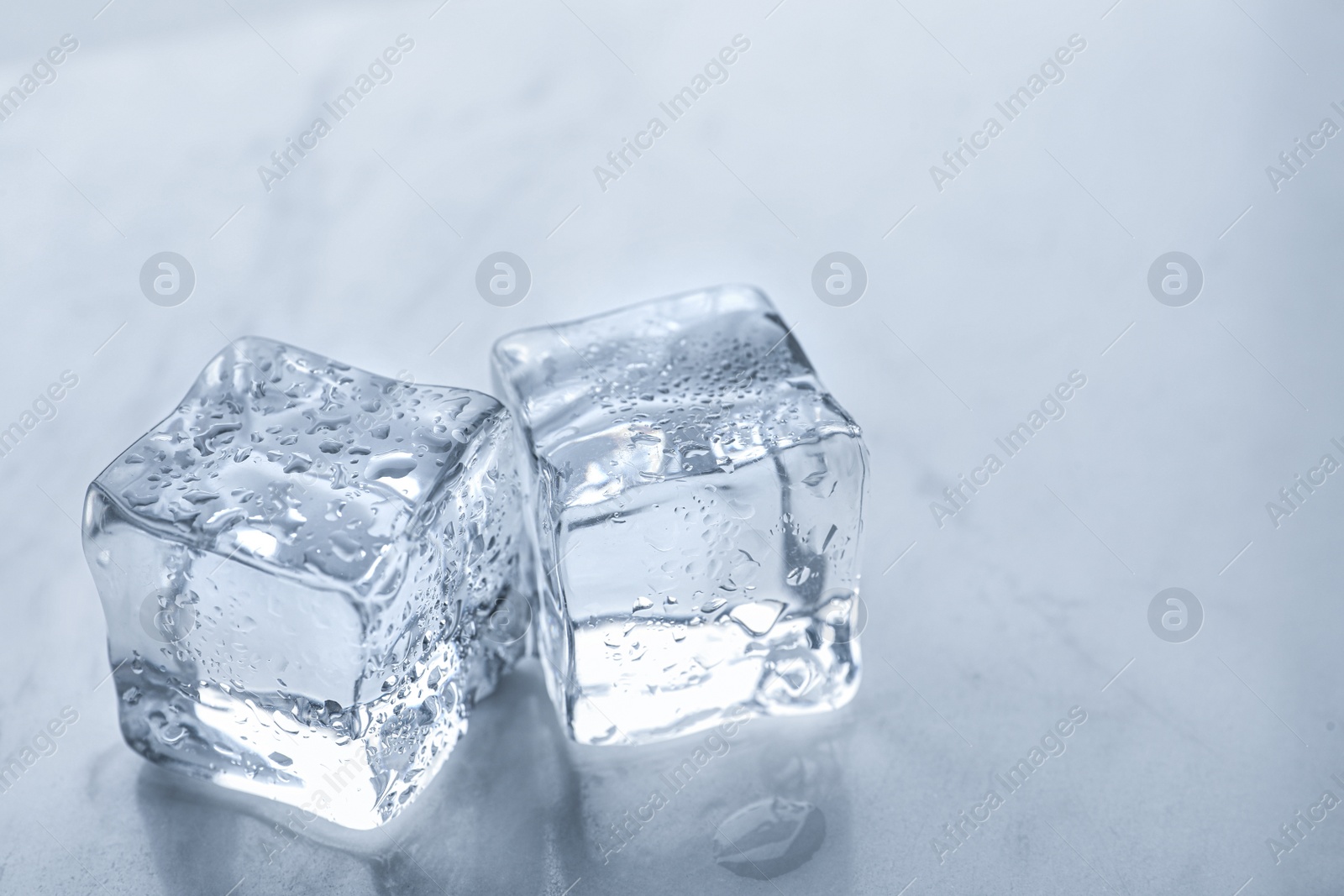 Photo of Crystal clear ice cubes with water drops on light table, closeup