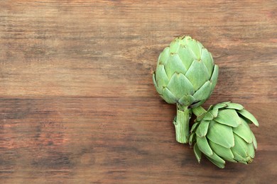 Fresh raw artichokes on wooden table, flat lay. Space for text