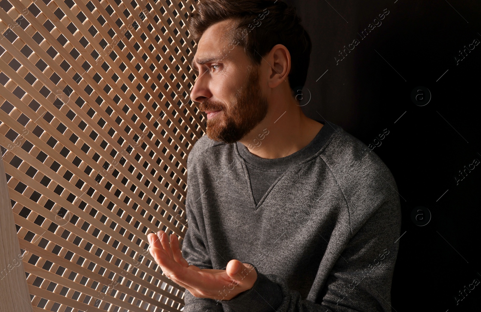Photo of Upset man talking to priest during confession in booth, space for text