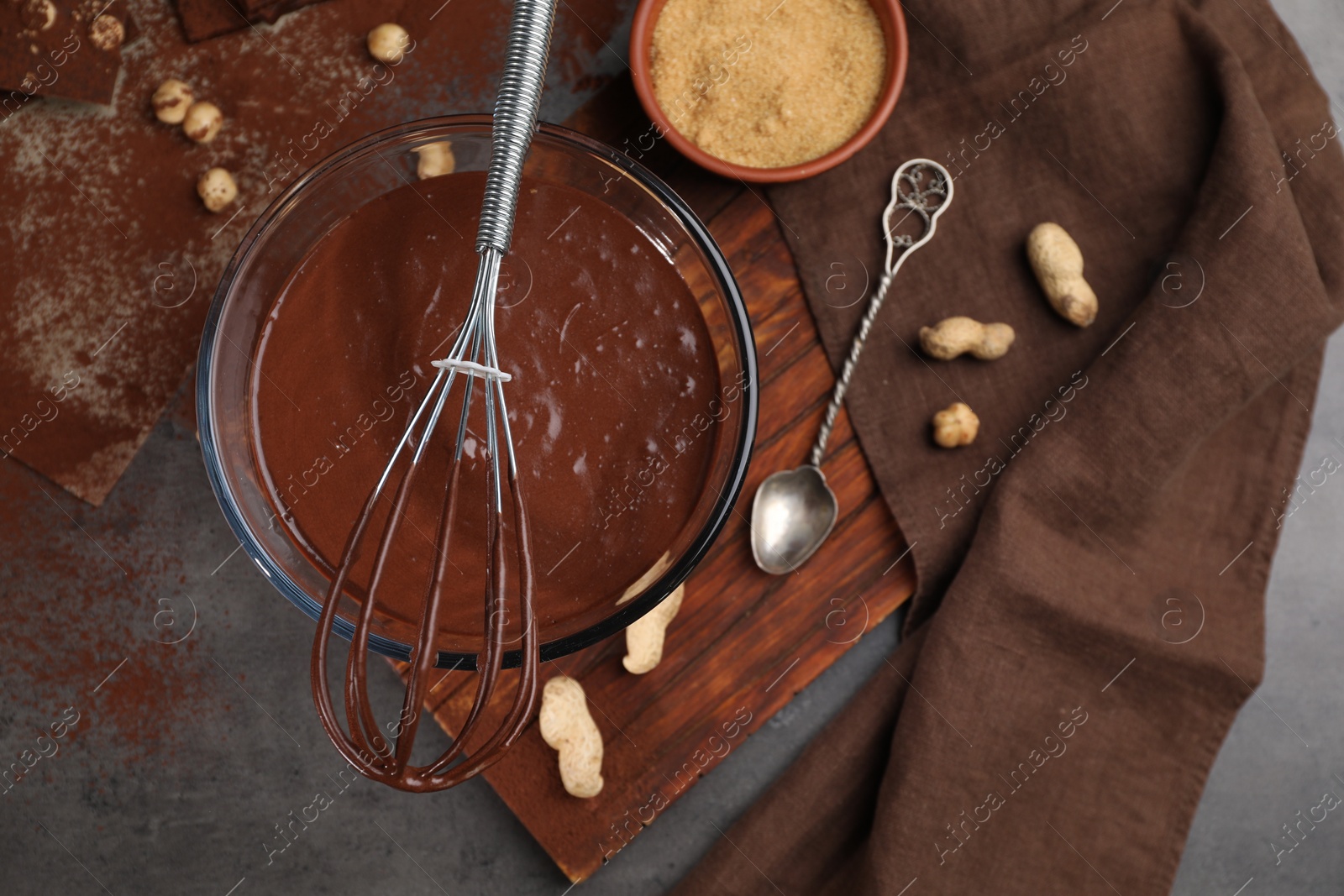 Photo of Bowl of chocolate cream, whisk and spoon on table, flat lay