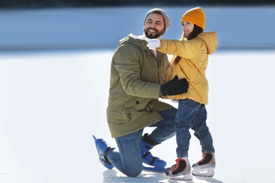 Image of Father and daughter spending time together at outdoor ice skating rink