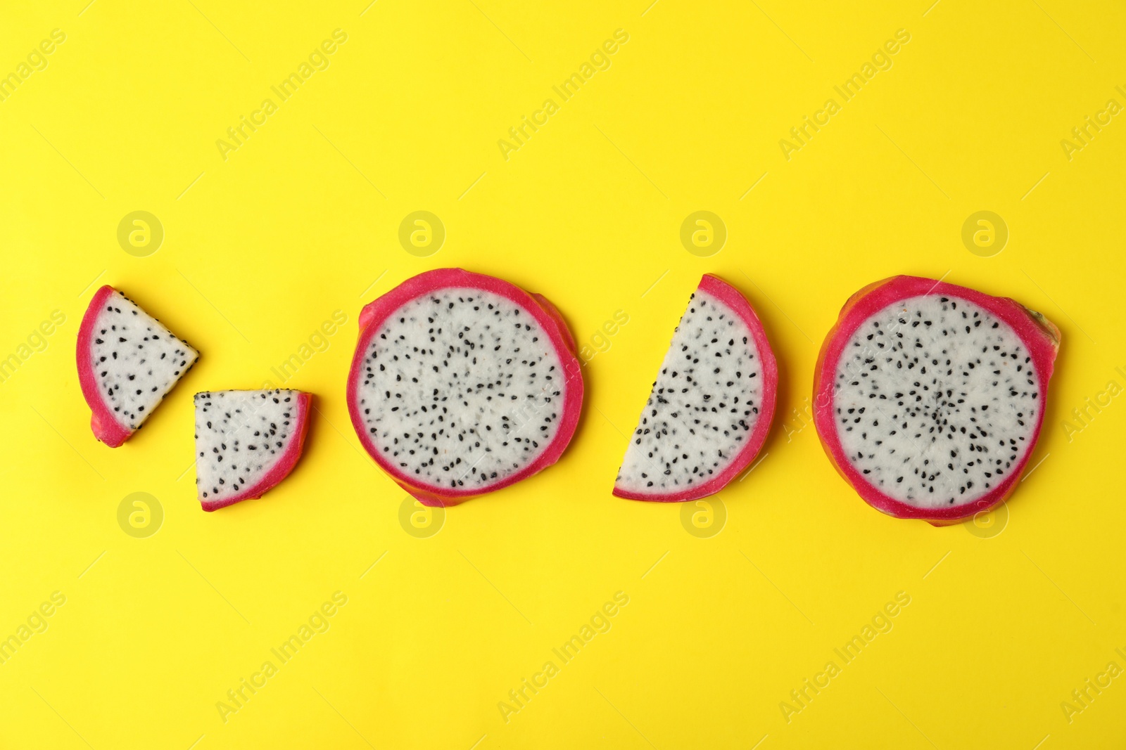 Photo of Delicious sliced dragon fruit (pitahaya) on yellow background, flat lay