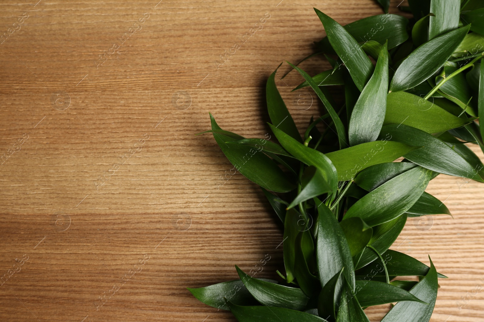 Photo of Beautiful handmade mistletoe wreath on wooden table, closeup. Space for text