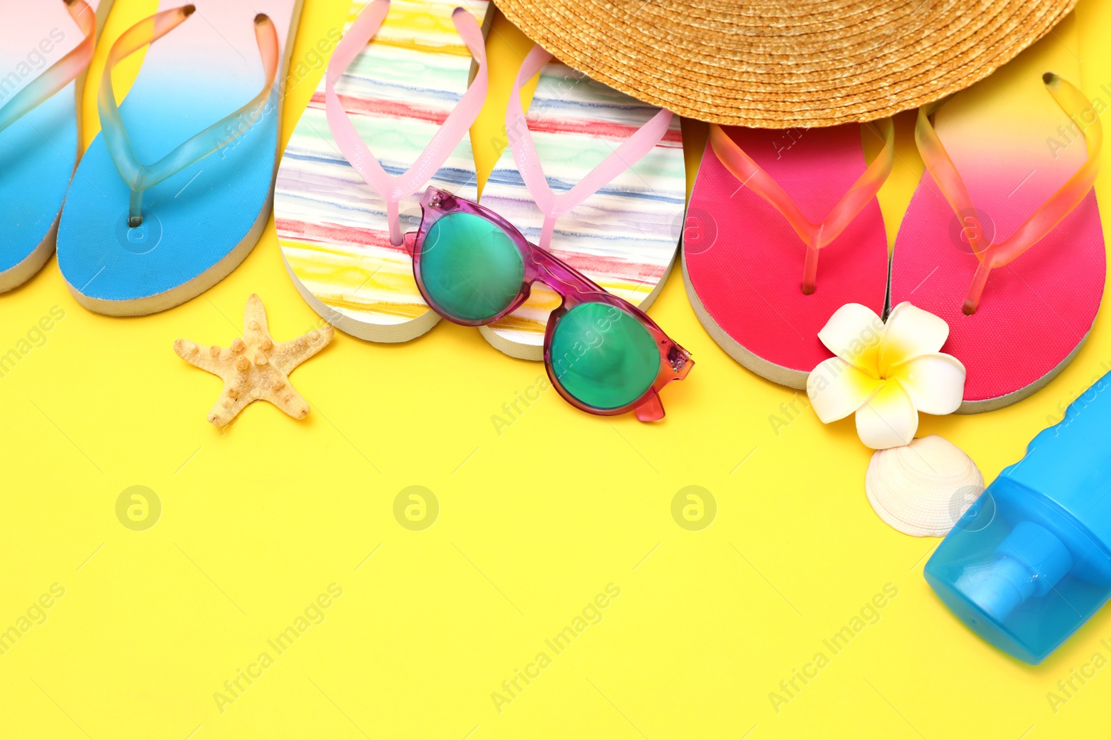 Photo of Set of different summer beach accessories on yellow background. Space for text