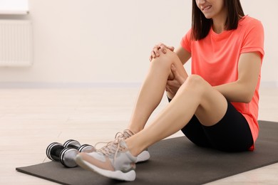 Photo of Woman suffering from leg pain on mat indoors, closeup. Space for text