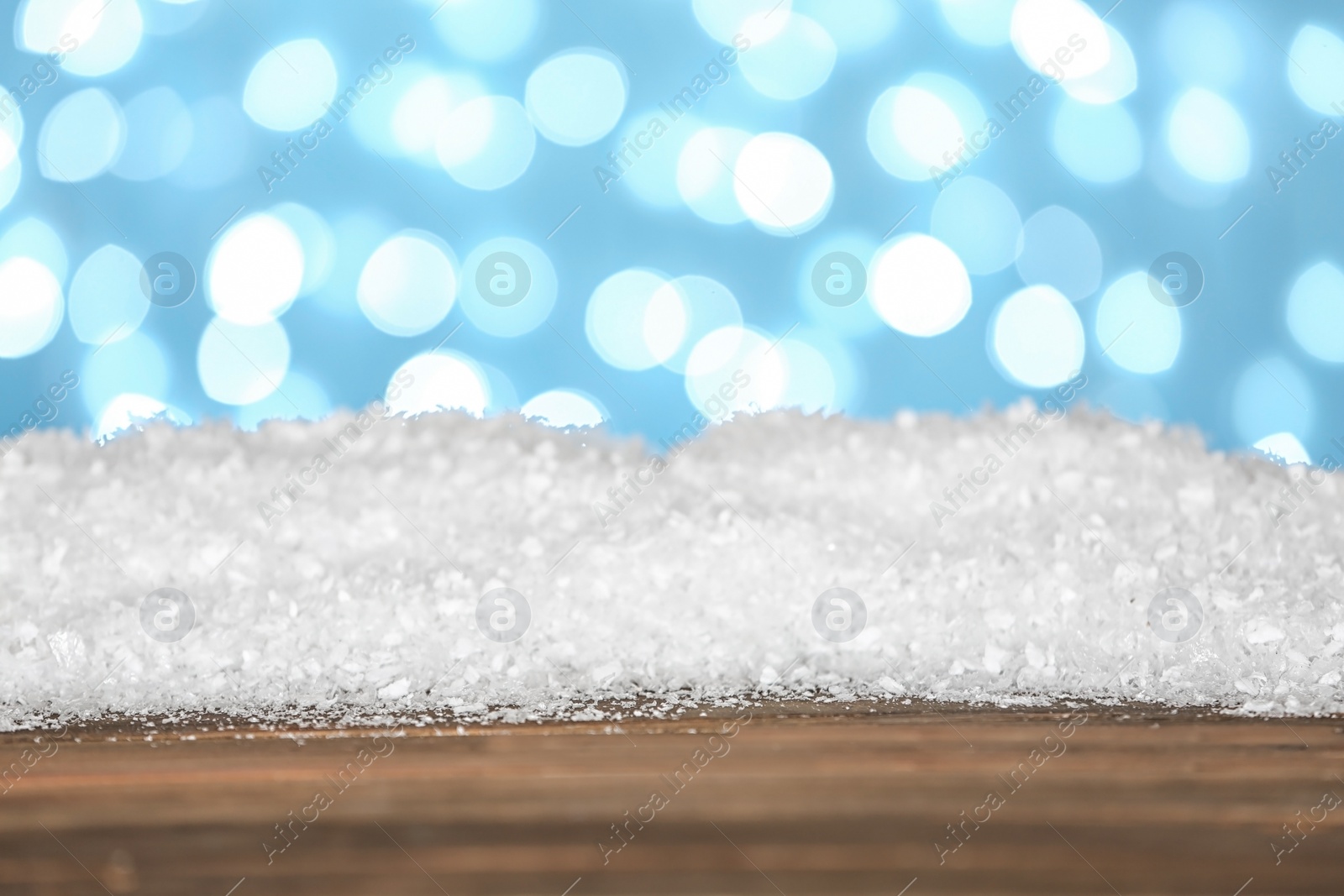 Photo of Heap of snow on wooden surface against blue background. Christmas season